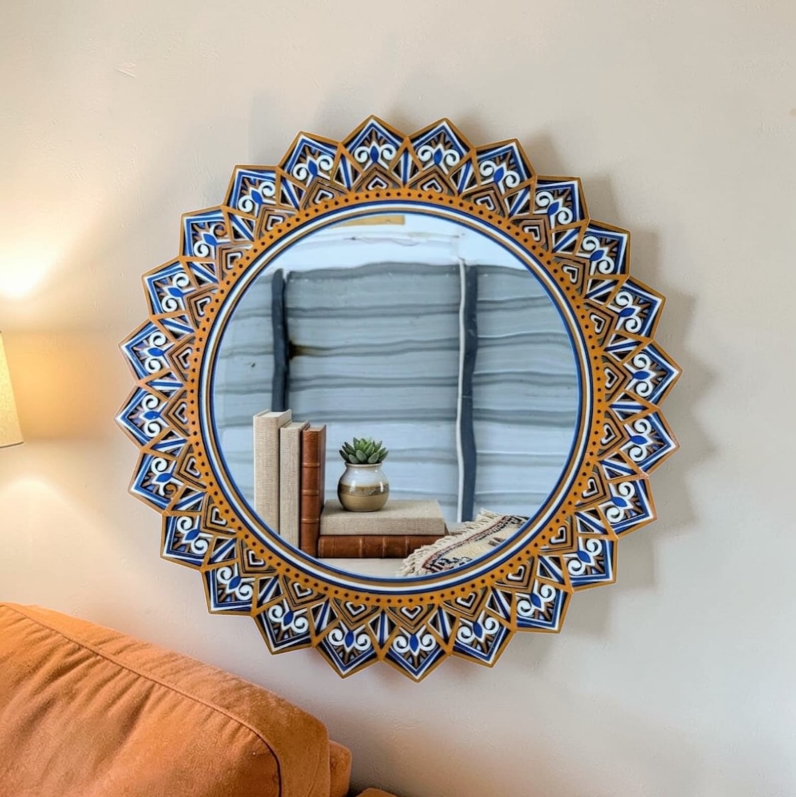 Decorative round mirror with a blue and gold frame on a wall.