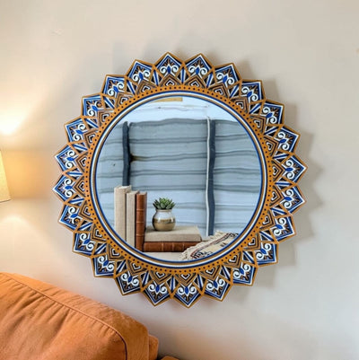 Decorative round mirror with a blue and gold frame on a wall.